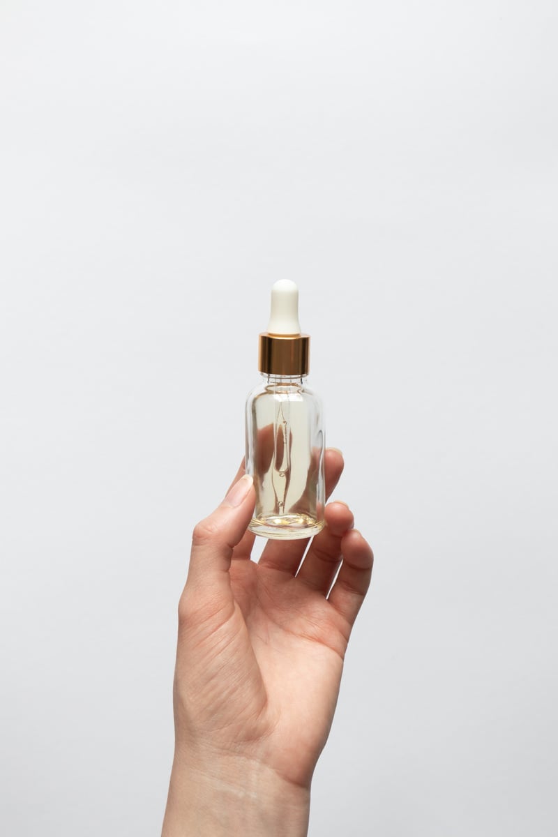 Female Hand Holding Glass Bottle with Essential Oil Serum 